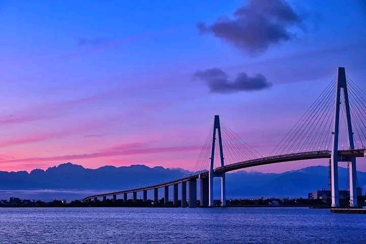 夕暮れの空に架かる大橋と遠くの山並み