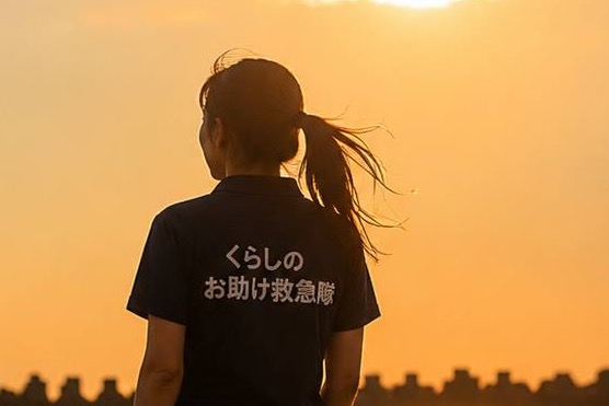 夕陽の海辺にたたずむ当店の女性スタッフの後ろ姿